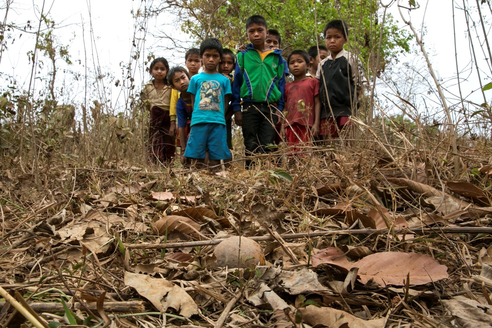 District de Toumlan, village de Nadoo Yai. Des enfants regardent une sous-munition non explosée qui a été trouvée près de leur village.