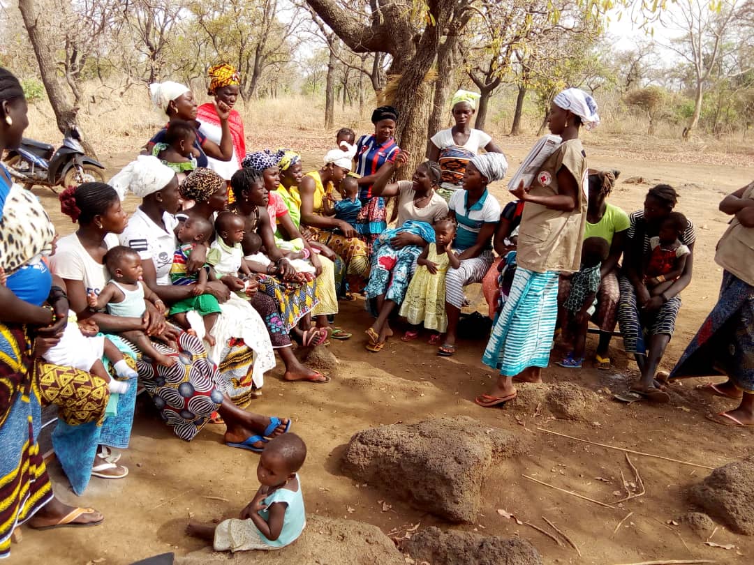 Au Burkina Faso, un groupe de femmes burkinabé discutent de l'alimentation et de la nutrition du nourrisson et du jeune enfant avec une volontaire de la Croix-Rouge.