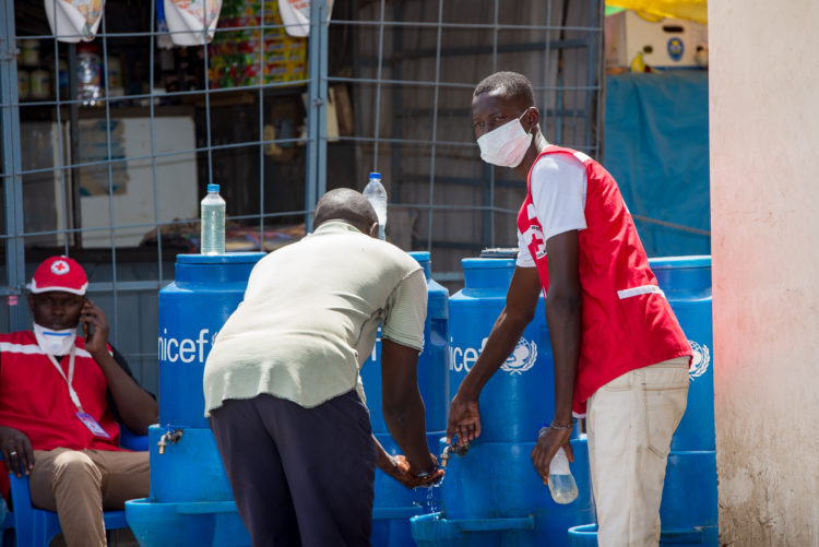 Les volontaires de la Croix-Rouge sénégalaise portant un masque font de la sensibilisation au lavage de mains.